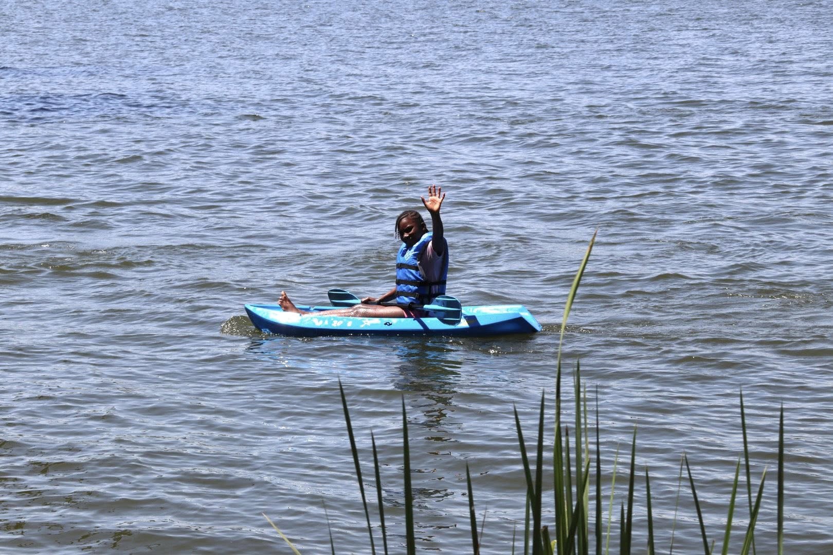 A girl waving from a kayak.